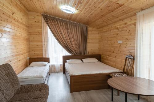 Habitación pequeña con 2 camas y mesa. en Tumar Mountain Guest House, en Karakol