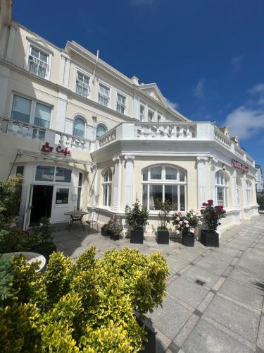 un gran edificio blanco con macetas delante de él en Eastbourne Riviera Hotel en Eastbourne