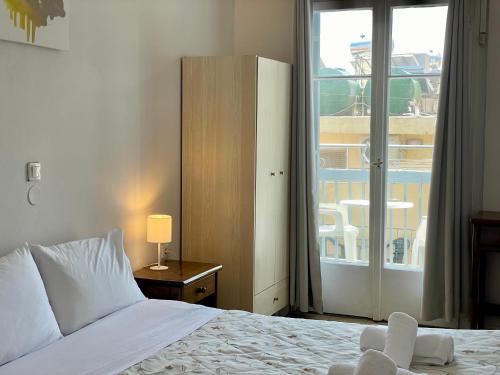 a bedroom with a bed and a window with a balcony at HB Hotel Benitsa in Benitses