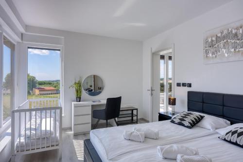 een witte slaapkamer met een groot bed en een bureau bij Villa-Osmium Galizana in Galižana