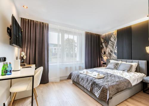 1 dormitorio con cama, escritorio y ventana en A&J APARTS GDYNIA en Gdynia