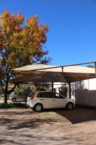 un coche blanco aparcado bajo una cubierta en un estacionamiento en Accommodation at Potch Guesthouse, en Potchefstroom