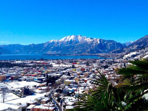 a view of a city with snow covered mountains at Ferienhaus Patrizia with a fantastic view of Lake Maggiore and the pool in Gordola