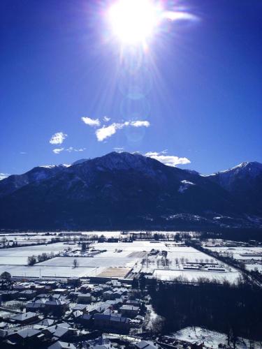 a sun shining over a snowy city with mountains in the background at Ferienhaus Patrizia with a fantastic view of Lake Maggiore and the pool in Gordola