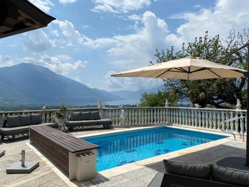 a swimming pool with an umbrella and chairs and a table at Ferienhaus Patrizia with a fantastic view of Lake Maggiore and the pool in Gordola