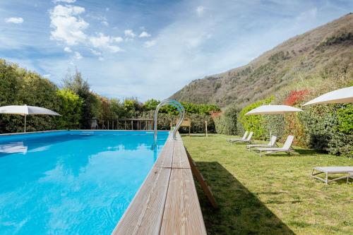 a pool with a wooden walkway leading to a house at Lucca Franco's Villa in Diecimo