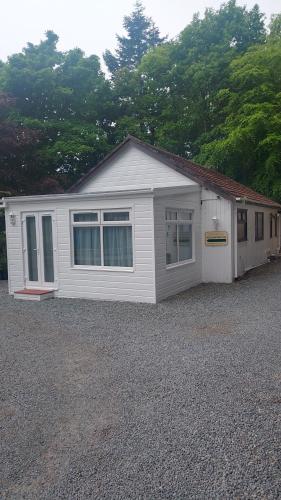 a white house with windows on a gravel lot at The Old Forestry Cottage in Portree