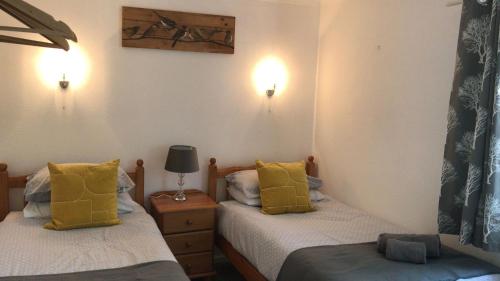 two beds in a room with yellow pillows at The Old Forestry Cottage in Portree