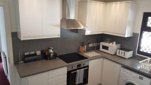 a kitchen with white cabinets and a microwave at The Old Forestry Cottage in Portree