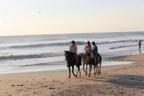 a group of people riding horses on the beach at Casa de la Naturaleza in Cóbano