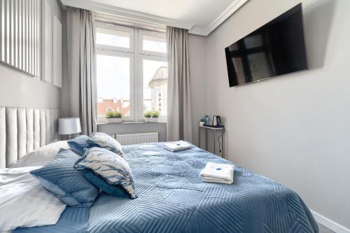 a bedroom with a blue bed with pillows and a television at Stawa Villa & Apart in Świnoujście