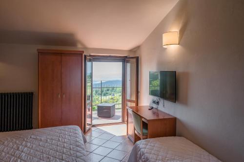 Hotel La Scottiglia e Ristorante في Seggiano: غرفة نوم بسريرين ومكتب فيه تلفزيون