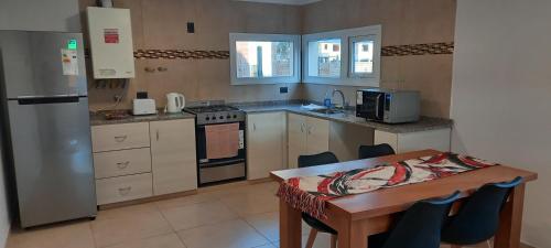 eine Küche mit einem Tisch und einem Kühlschrank sowie einem Tisch und Stühlen in der Unterkunft PH Design Entre Pinos in San Carlos de Bariloche