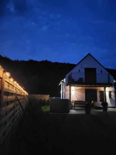 ein nachts beleuchtetes Haus mit einem Zaun in der Unterkunft Domki u Duszy in Brenna