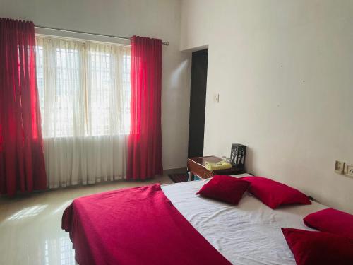 a bedroom with a bed with red sheets and a window at Rose Garden home stay Thrissur in Trichūr