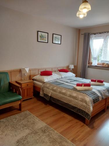 a bedroom with a bed and a green chair at Pokoje Gościnne ZYCH in Chochołów