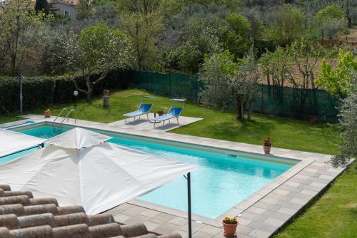 a swimming pool with an umbrella and some chairs at Casa Galina in Civitella in Val di Chiana