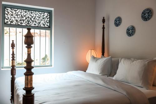 a bedroom with a bed and a window with plates on the wall at Moi Talpe by DBI in Talpe