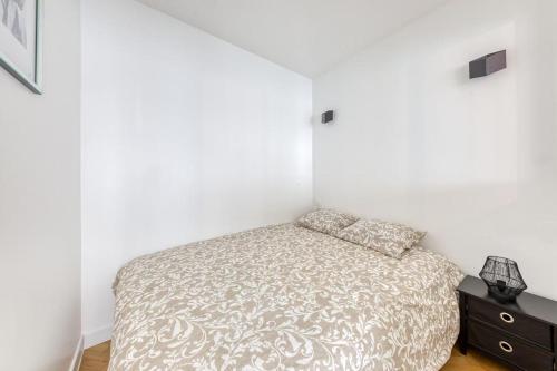 a white bedroom with a bed and a night stand at L'Appartement d'Art et de Lumière in Clichy