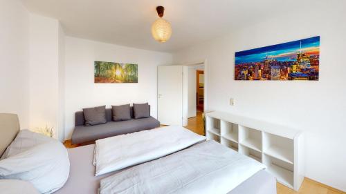um quarto branco com uma cama e um sofá em Helle Ferienwohnung in 1a Lage em Leipzig