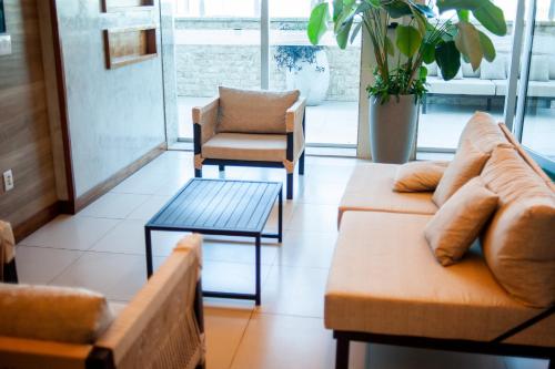 a living room with couches and a chair at Paradiso Macae Hotel in Macaé