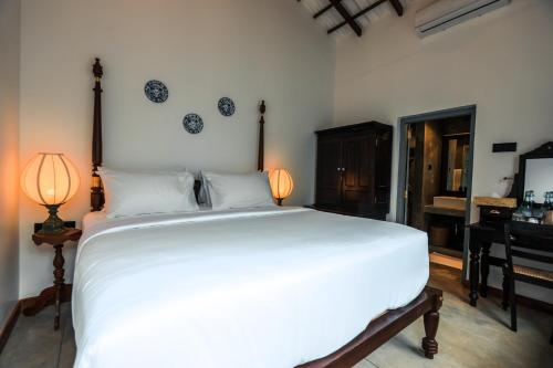 a bedroom with a large white bed and a piano at Moi Talpe by DBI in Talpe