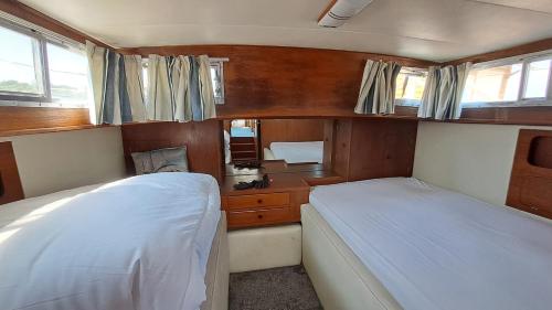 a small bedroom with two beds and a desk at The Rose - 37ft Lakeside Yacht with Hot Tub in Swansea