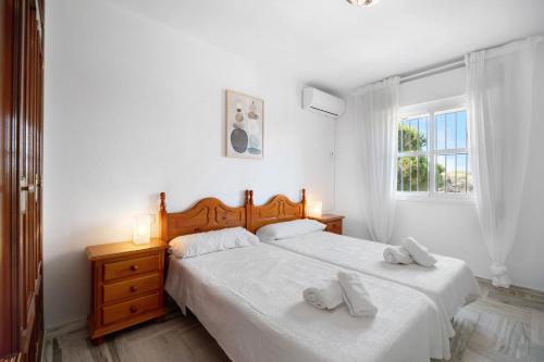 a white bedroom with two beds and a window at Virgen del Camino 1a línea de playa in Chiclana de la Frontera