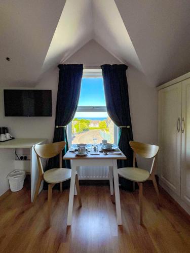 a table and chairs in a room with a window at Mount Edwards Hill Guest Accommodation in Cushendall
