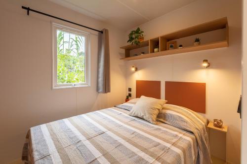 um quarto com uma cama e uma janela em Le Palmier, mobil-home sans vis-à-vis idéalement situé entre mer et vignes em Hyères