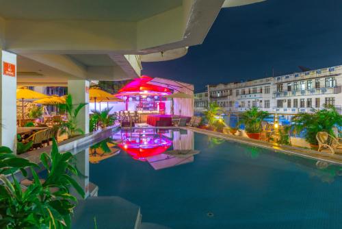 a hotel swimming pool with tables and umbrellas at night at Hotel Sapphire in Mombasa