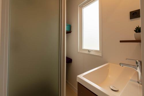 une salle de bain avec un lavabo et une fenêtre dans l'établissement Le Palmier, mobil-home sans vis-à-vis idéalement situé entre mer et vignes, à Hyères
