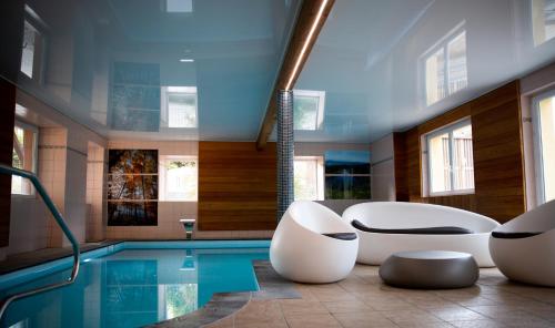 un bagno con piscina, 2 sedie e vasca di Logis Hôtel Restaurant De La Poste et SPA de Montagne a Le Bonhomme
