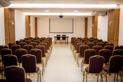 an empty conference room with chairs and a screen at Paradiso Macae Hotel in Macaé