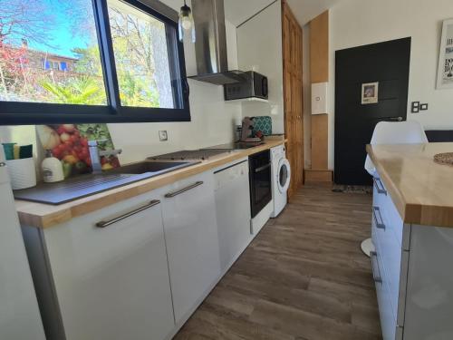 a kitchen with white cabinets and a sink at PAUSE NATURE. Maison Ananda à 14 kms de Toulouse avec parking privatif in Lapeyrouse-Fossat