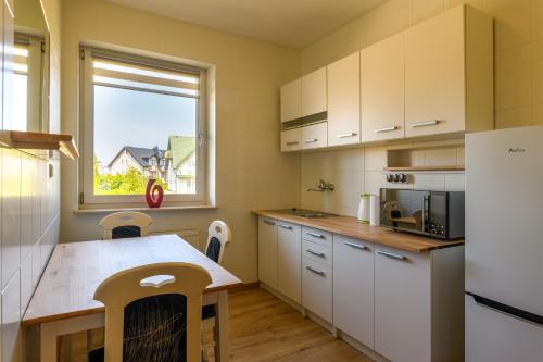 a kitchen with white cabinets and a table and a window at Rubin-Chłapowo in Władysławowo