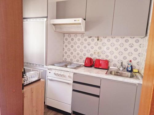 Elle comprend une petite cuisine équipée d'appareils électroménagers blancs et d'un évier. dans l'établissement Wasserfälle Apartments, à Sasbachwalden
