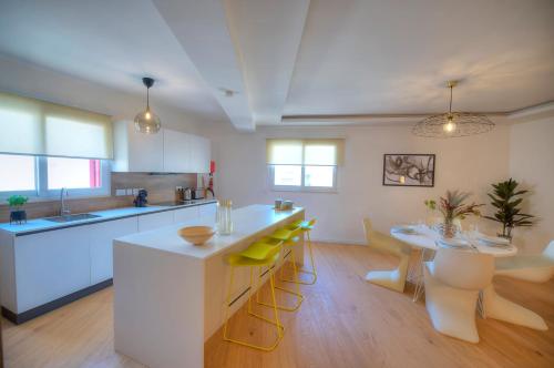 uma cozinha com uma ilha branca e uma mesa com cadeiras amarelas em Large & beautifully furnished 2 bedrooms ABON1-1 em Sliema