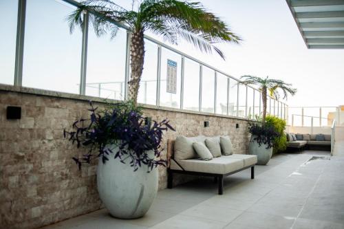 a patio with a couch and palm trees on a building at Paradiso Macae Hotel in Macaé