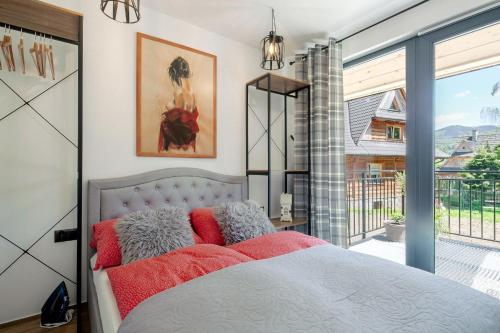 een slaapkamer met een bed met rode kussens bij Domek w Borze in Kościelisko