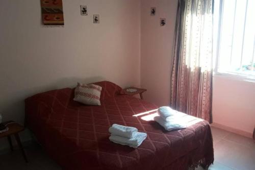 Un dormitorio con una cama roja con toallas. en Casa en cercanías del Parque Gral. San Martín en 