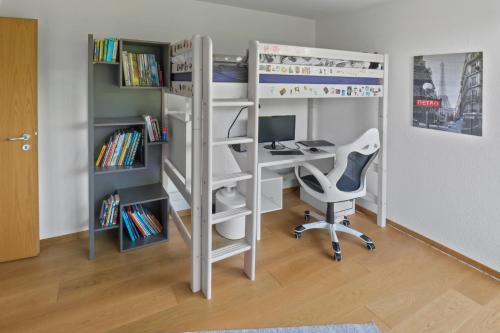 a room with a bunk bed and a desk with a computer at Magnifique villa avec piscine et vue sur le lac in Cudrefin