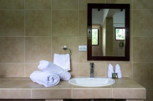 a bathroom with a sink and a mirror and towels at Fuego del Sol Beachfront Hotel in Jacó