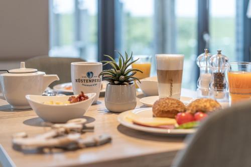 einen Holztisch mit Teller mit Speisen und Getränken in der Unterkunft Küstenperle Strandhotel & Spa in Büsum