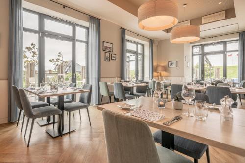 a restaurant with tables and chairs and windows at Küstenperle Strandhotel & Spa in Büsum