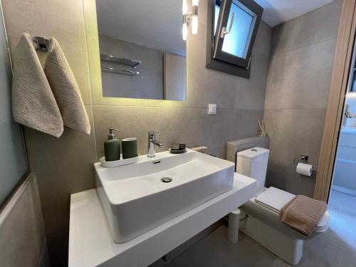 a bathroom with a white sink and a toilet at VERA VITA APARTMENTS in Skala Rachoniou
