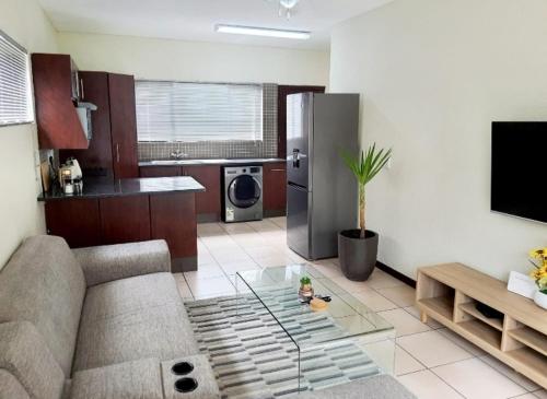 a living room with a couch and a stainless steel refrigerator at NST City Apartments @ 9 Joubert in Nelspruit