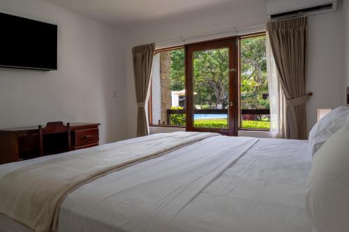 a bedroom with a large white bed and a large window at Fuego del Sol Beachfront Hotel in Jacó