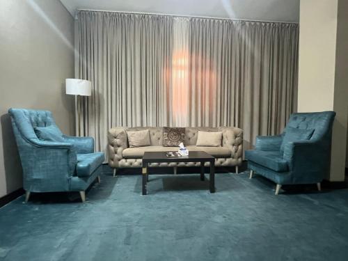 ein Wohnzimmer mit einem Sofa und 2 Stühlen in der Unterkunft Crystal Blue Hotel in Rabigh