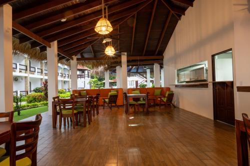 a dining room with tables and chairs and a kitchen at Fuego del Sol Beachfront Hotel in Jacó